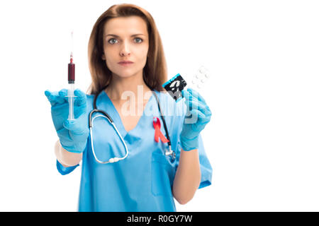Attractive doctor avec ruban rouge montrant avec le sang et seringue préservatif avec pills isolé sur blanc, concept de la journée mondiale du sida Banque D'Images