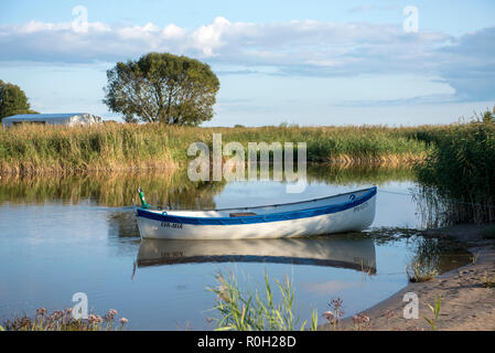 Bateau solitaire dans le quartier tranquille de rushy backwater éclairées par le soleil du soir Banque D'Images