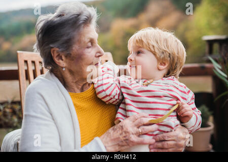 Vieille Femme avec un enfant en arrière-petits sur une terrasse à l'automne. Banque D'Images