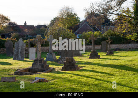 De longues ombres les pierres tombales dans le cimetière de l'église de St Mary the Virgin, Steeple Ashton, Wiltshire, Royaume-Uni. Banque D'Images