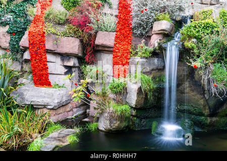À pied madère cascade à Ramsgate, dans le Kent avec un hommage de coquelicots pour le 100e anniversaire de la fin de la première guerre mondiale. Deux longues de gouttelettes de coquelicots tricoté pendant vers le bas sur les rochers, avec une cascade à côté. Banque D'Images
