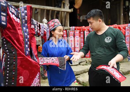 (181105) -- QIANDONGNAN, le 5 novembre 2018 (Xinhua) -- Jialong Sunshine Yang (L) montre un costume Miao brodé d'un client à Xinjiang Village de Taijiang Comté de Qiandongnan Préfecture autonome Miao et Dong, au sud-ouest de la province du Guizhou, en Chine, le 4 novembre 2018. Né avec une perte auditive, Yang, Jialong Sunshine 28, est une femelle de l'ethnie Miao, qui sont engagés dans la broderie Miao au village. Elle a appris la broderie de sa mère alors qu'elle n'était qu'un enfant, et a été un maître bien connu maintenant. (Xinhua/Liu Kaifu) (SXK) Banque D'Images