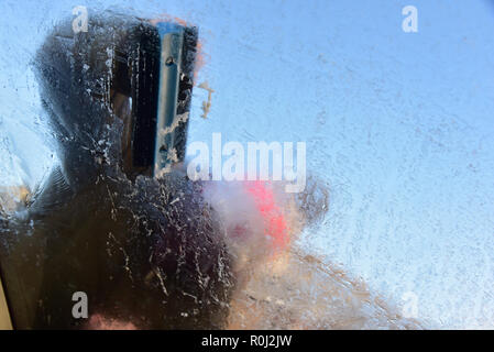 Beaucoup de pays de Galles s'est réveillé ce matin à la couche de givre de surface couvrant les pare-brise de voiture et des températures de gel. retrait de la glace d'un pare-brise de voiture Banque D'Images