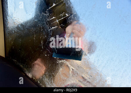 Beaucoup de pays de Galles s'est réveillé ce matin à la couche de givre de surface couvrant les pare-brise de voiture et des températures de gel. retrait de la glace d'un pare-brise de voiture Banque D'Images