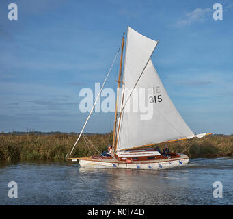 Un bateau à voile Sloop fractionnaire avec voiles blanches sur la rivière Thurne, sur un matin d'automne, Norfolk Broads, Norfolk, England, UK Banque D'Images