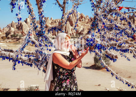 Jeune fille près de vieil arbre décoré avec le blue-eyes - amulettes Nazars, faite de verre bleu. Protéger contre le mauvais œil en parc national de Göreme, Cappadoci Banque D'Images