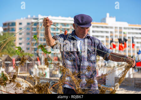 Le pêcheur local qui tend ses filets de pêche sur la plage de Monte Gordo, Algarve, Portugal Banque D'Images