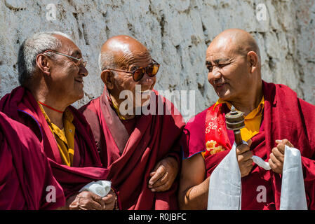 Trois moines de Lamayuru Gompa, le plus ancien et le plus grand monastère existant au Ladakh, portant des vêtements, discutent à la cour. Banque D'Images