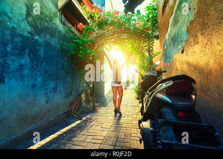 Silhouette d'une belle jeune fille sur un fond coucher de voyager à travers les rues étroites de l'Indonésie Bali tropical Banque D'Images