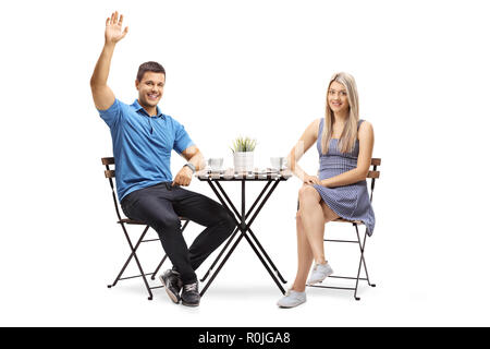 Jeune couple assis à une table de café, l'homme forme isolé sur fond blanc Banque D'Images