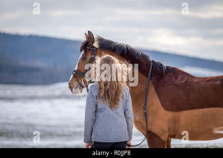 Charmante fille à sur son cheval dans le champ neigeux Banque D'Images