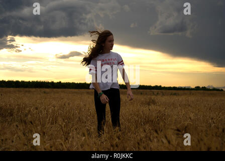 Belle jeune femme rousse posant dans un champ de blé. Jour nuageux. Adolescent Banque D'Images