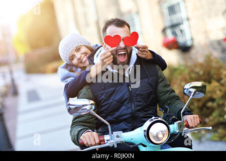 Beau young couple holding coeurs tout en riding scooter en ville à l'automne Banque D'Images