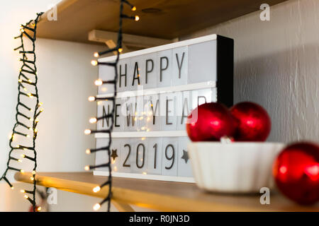 Sur le plateau en bois blanc en lettres noires la nouvelle année 2019. Garland et boules de Noël rouge dans une assiette blanche. Banque D'Images