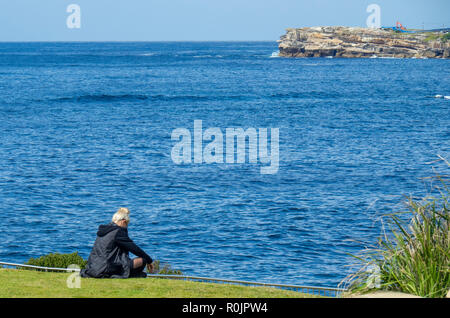 L'âge moyen du Caucase l'homme assis à la périphérie de dauphins à regarder le point de l'océan Pacifique Sydney NSW Australie. Banque D'Images