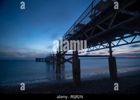 A broken et jetée désaffectée à Totland bay dans l'île de Wight avec le ciel de nuit et une mer calme à l'arrière-plan Banque D'Images