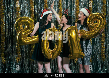 Mesdames avec santa chapeaux et costumes des cerfs s'amuser danser avec de l'or 2019 Nouvelle année ballon sur partie. Heureux belle attrayante winsome glamorous gor Banque D'Images