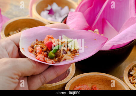 Envelopper d'une bouchée avec red lotus petal (Haspres Kam) qu'isThai et le Laos est snack traditionnel sur la table en bois Banque D'Images