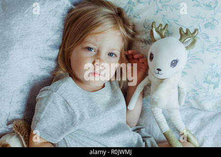 Enfant girl lying in bed with teddy bear Banque D'Images