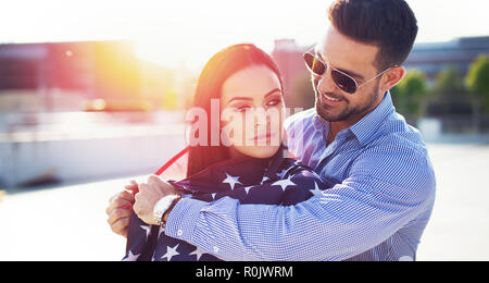 Jeune homme femme couvrant avec USA drapeau dans le coucher du soleil en plein air Banque D'Images