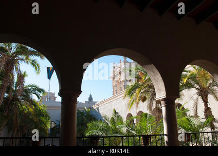 Vue sur le jardin de palmiers et la tour du palais à travers les arcades du palais de pierre blanche. Palais riche de style espagnol Banque D'Images