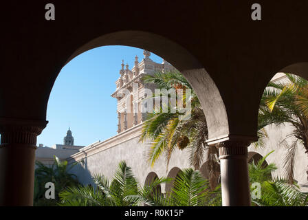 Vue sur le jardin de palmiers et la tour du palais à travers les arcades du palais de pierre blanche. Palais riche de style espagnol Banque D'Images