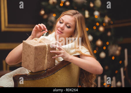 Une jeune femme dans un tricot robe blanche est assis dans une chaise ancienne. L'attente pour Noël Banque D'Images