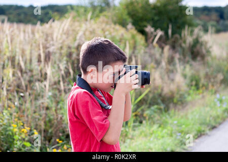 Un portrait d'un jeune garçon, tenant un appareil photo numérique moderne Banque D'Images