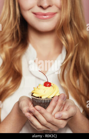 Femme mains tenant un délicieux petit gâteau avec une cerise sur le gâteau, Close up. Banque D'Images