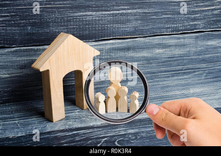 À la loupe à la grande famille est debout près de la maison. Figures en bois de personnes sont près d'une maison en bois. Le concept d'un couple Banque D'Images