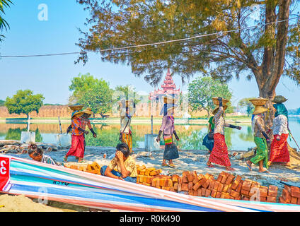 MANDALAY, MYANMAR - février 23, 2018 : Le groupe de femmes des travailleurs portent sur leurs têtes des pierres et autres matériaux pour la réparation des routes, le 23 février en M Banque D'Images