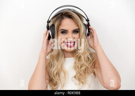 Portrait d'une jeune femme chanteuse avec écouteurs. Écouter de la musique. Chanter avec une expression de bonheur Banque D'Images