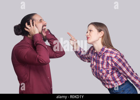 Vue côté profil portrait de femme debout en colère et le blâme à crier malheureux avec cheveux noir recueillies. Piscine studio shot, isolé sur le gra Banque D'Images