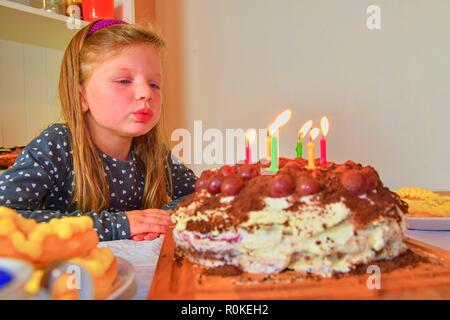 Little girl blowing out candles sur son gâteau d'anniversaire. Petite fille fête ses six ans. Gâteau d'anniversaire et petite fille Banque D'Images