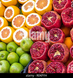 Stand de vente de jus de pommes, oranges et de grenadiers avec les fruits tranchés Banque D'Images