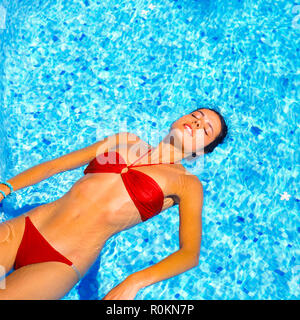 Jeune femme avec bandeau rouge flottant sur l'eau dans la piscine, Guadeloupe, French West Indies, Banque D'Images