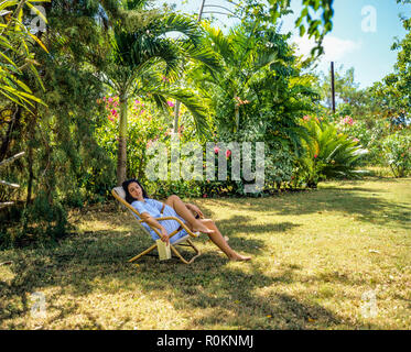 Jeune femme sieste dans une chaise longue, d'un jardin tropical, Guadeloupe, French West Indies, Banque D'Images