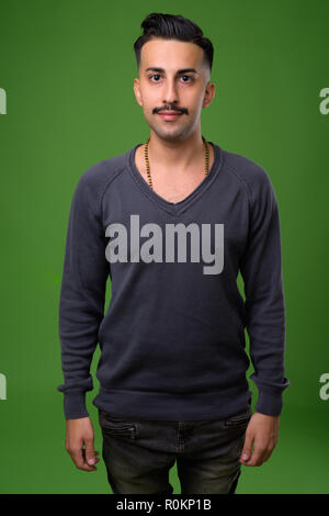 Beau jeune homme iranien avec moustache contre green backgroun Banque D'Images