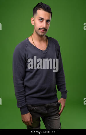 Beau jeune homme iranien avec moustache contre green backgroun Banque D'Images