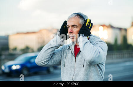 Mâle mature runner de mettre le casque à l'extérieur dans la ville. Banque D'Images