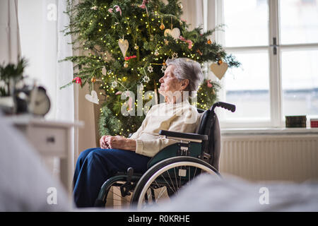 A senior woman in wheelchair at home à l'époque de Noël. Banque D'Images