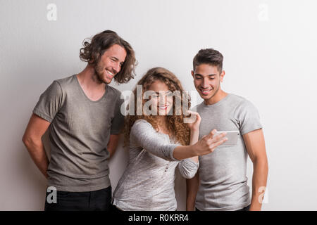 Portrait de jeunes amis joyeux debout dans un studio, en tenant. selfies Banque D'Images