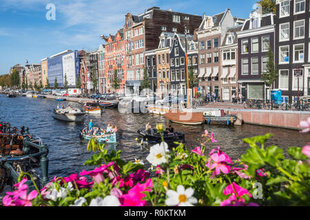 Vue d'un canal à Amsterdam avec des bateaux de touristes au fil des fleurs colorées sur le pont Banque D'Images