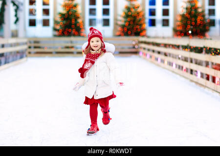 Enfants patinage sur glace en hiver park rink. Enfants patin à glace sur la foire de Noël. Petite fille en patins sur jour de neige froide. Plaisir de la neige pour l'enfant. Gagner Banque D'Images