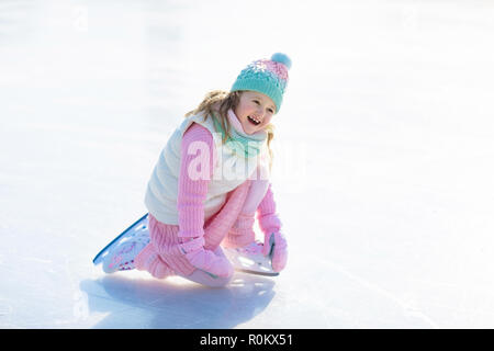 Enfant patinage sur glace naturelle aux beaux jours d'hiver. Enfants avec des patins. Petite fille patinage sur lac gelé dans le parc enneigé. La neige et l'hiver. À sain Banque D'Images