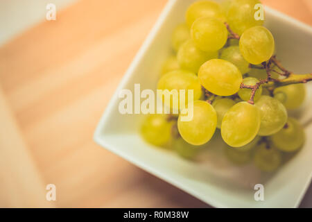 Bouquet de raisin vert dans le panier, fruits de l'automne, un symbole d'abondance sur fond de bois rustique avec copie espace, vue du dessus, close-up. Banque D'Images