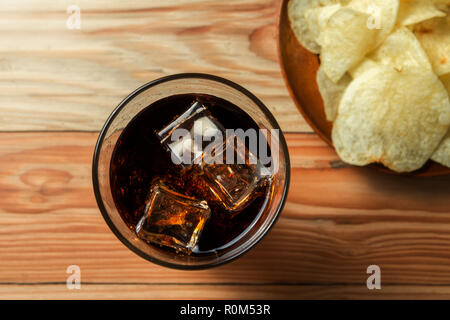 Croustilles de pommes de terre avec cola sur un fond de bois Banque D'Images