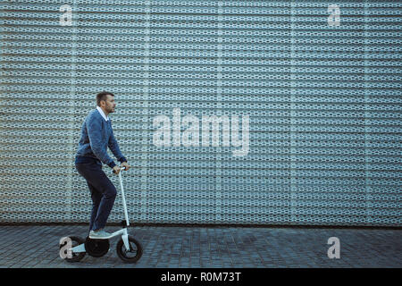 Vue de côté de l'homme pousser scooter de coup sur un remblai magnifique Banque D'Images