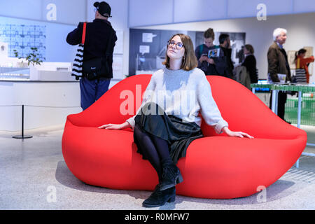 Le Design Museum, Londres, Royaume-Uni, 6ème Nov 2018. Une employée du musée essaie le Bocca Sofa (1970) par le studio '65. Réunissant les spéculations d'avant-garde avec des objets contemporains et de nouvelles commissions, sociétés d'aide à domicile d'aujourd'hui explore home à travers le prisme de l'imagination d'hier. L'exposition se tiendra du 7 novembre 2018 au 24 mars 2019. Credit : Imageplotter News et Sports/Alamy Live News Banque D'Images