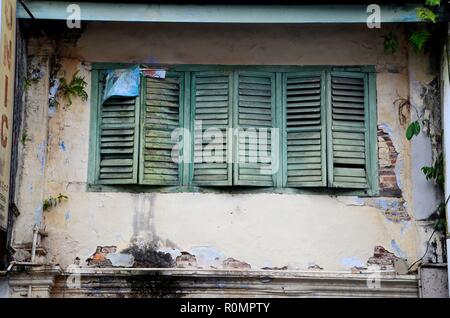 Volets en bois bleu-vert sur les fenêtres avec écaillage texturé Peinture Kuching Malaisie Banque D'Images